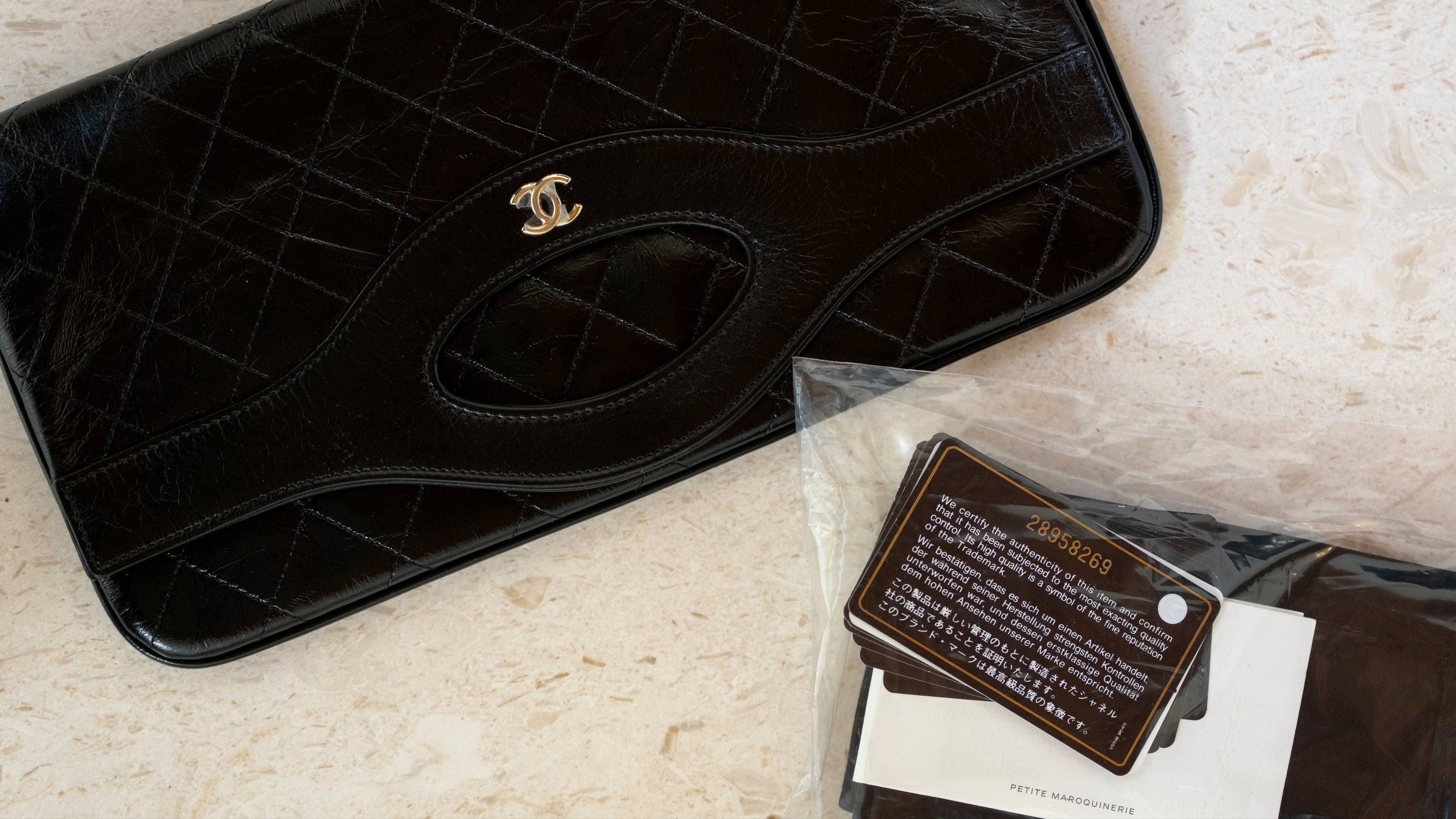 Black quilted handbag with gold logo on a light surface