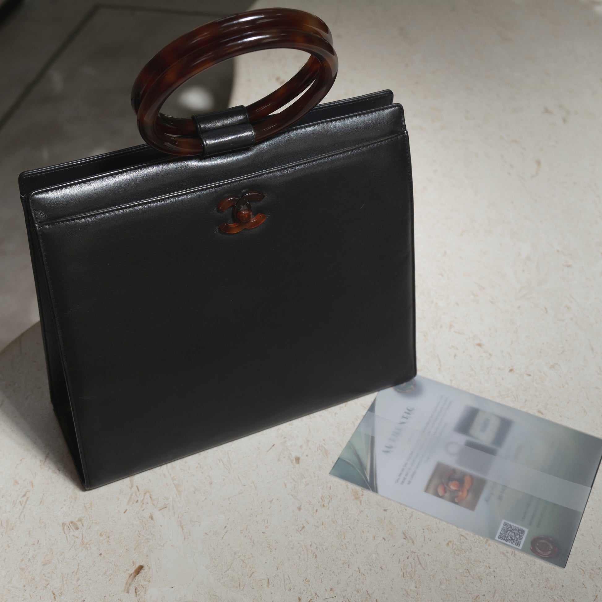 Black handbag with tortoiseshell handle on a light surface