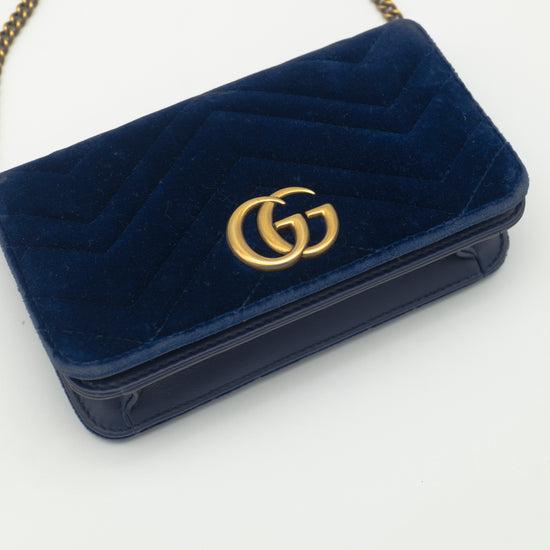 Navy blue velvet handbag with gold logo on a white background