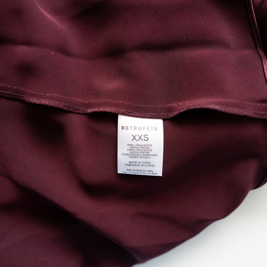 Close-up of a maroon garment with a 'Retrofete' label on a white background