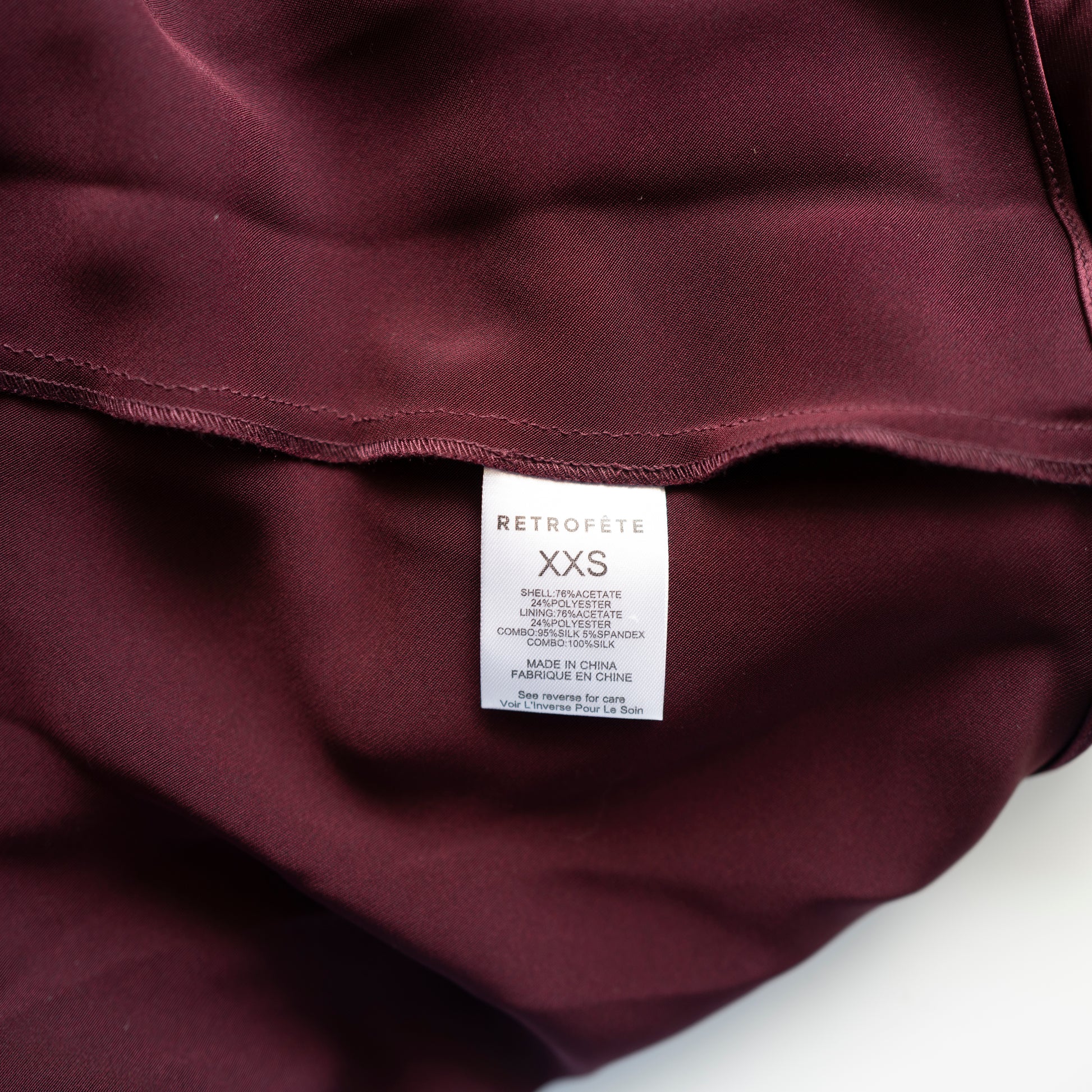 Close-up of a maroon garment with a 'Retrofete' label on a white background