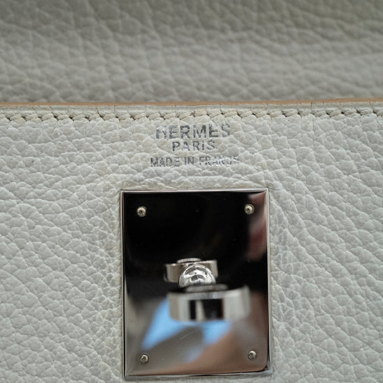 Close-up of a Hermès Paris bag with a silver clasp on a light gray leather background.