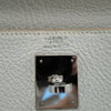 Close-up of a Hermès Paris bag with a silver clasp on a light gray leather background.