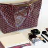 Burgundy Goyard tote with makeup items on a white surface
